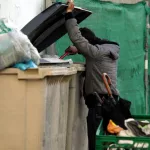 Un ciudadao busca restos en un contenedor de basura