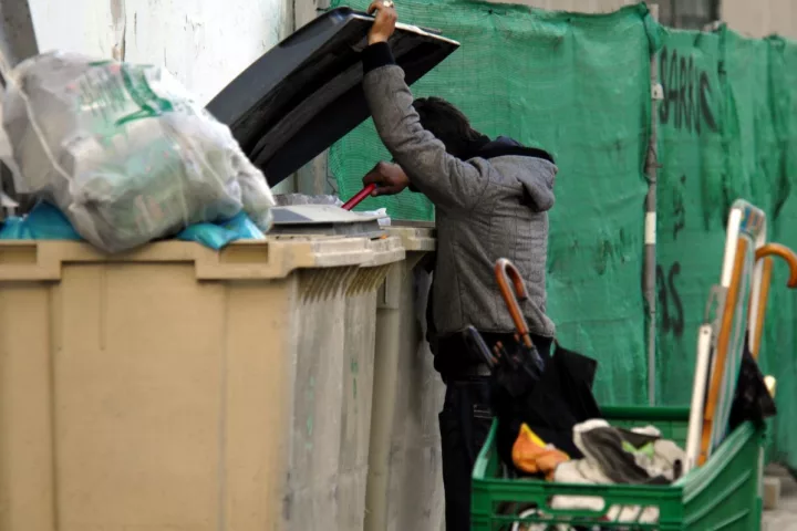 Un ciudadao busca restos en un contenedor de basura