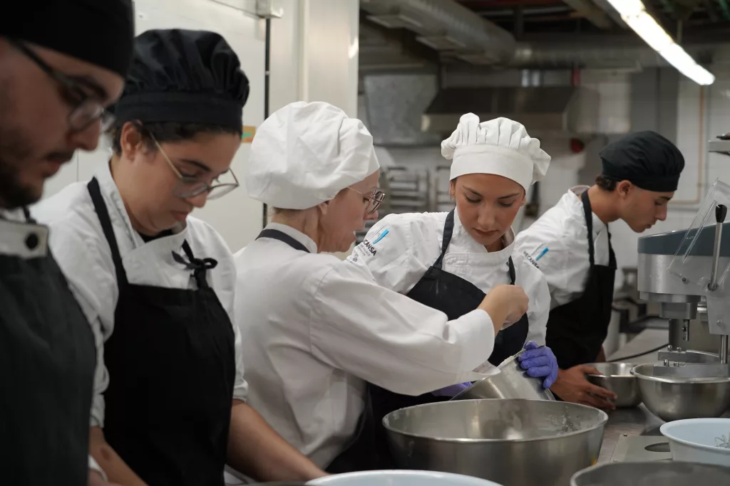 Estudiantes de Hecansa en una práctica en cocina reciben explicaciones de una docente.