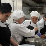 Estudiantes de Hecansa en una práctica en cocina reciben explicaciones de una docente.